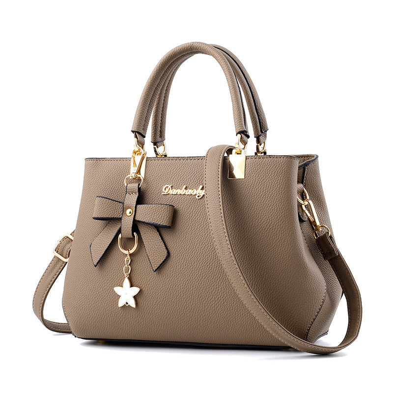 Bowtie top-handle crossbody satchel by Solenne, held in hand